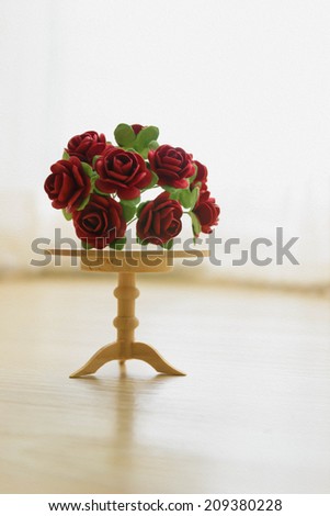 painting miniature red roses on a wooden table. beautiful small world