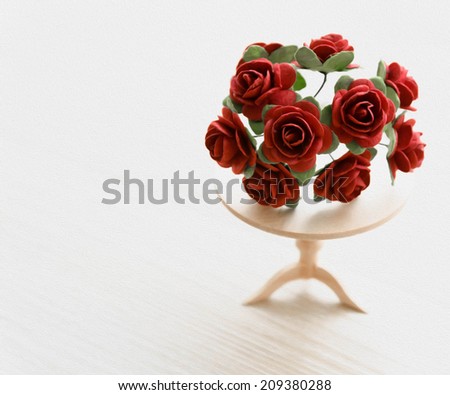 painting miniature red roses on a wooden table. beautiful small world
