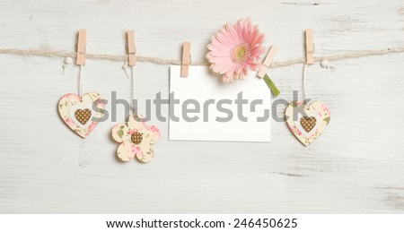 Heart, flowers and sign on clothesline on white wooden background