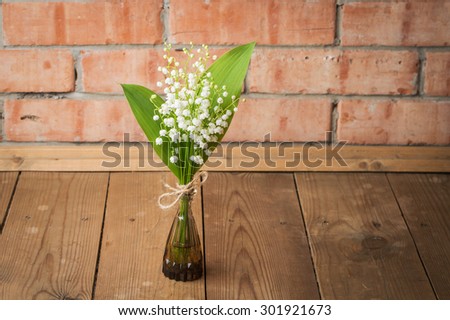 Bouquet lilies of the valley on a background of a brick wall