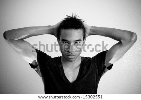 a young african american male pulls his hair back while focusing on what is in front of him
