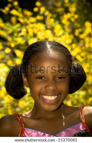 a young african american girl with a big smile against beautiful yellow flowers
