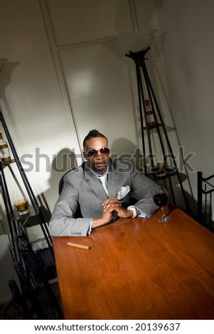 young african american adult in suit with a glass of merlot and a cigar