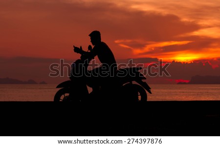 black silhouette of biker on orange sunset sky background.