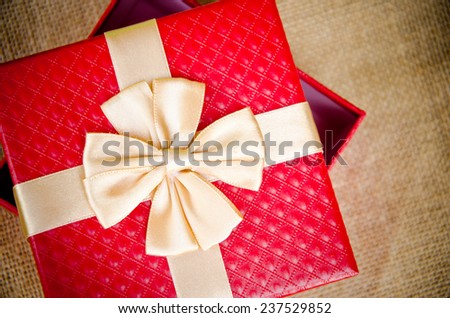 Red gift box with gold  ribbon on sack background
