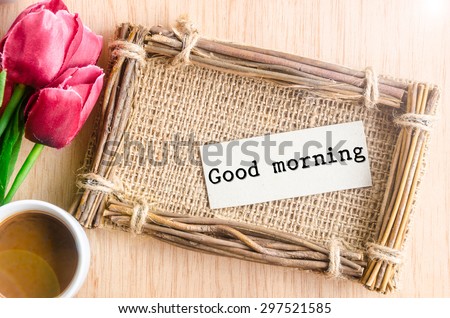 Good morning paper tag in sack photo frame and coffee with red tulip on wooden background.