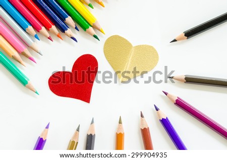 Color pencils and paper heart shape on white background.