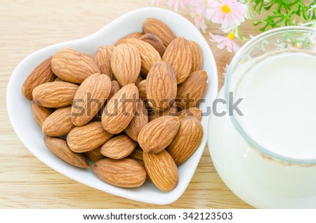 Almond milk with almond on a white bowl cup with flower on sack background.