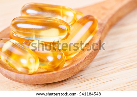 Cod liver oil omega 3 gel capsules on wooden background