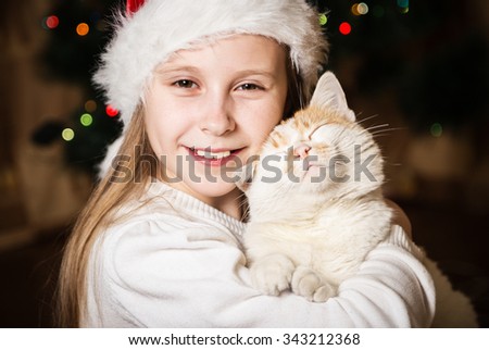 Cute little girl hugging her cat in Christmas