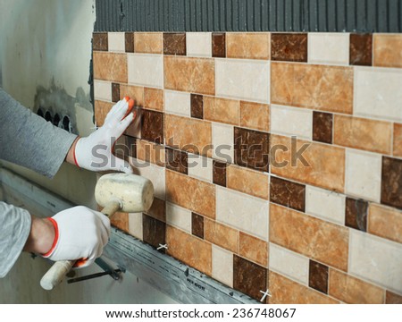 Laying Ceramic Tiles. Tiler knocking on the tiles with a rubber mallet