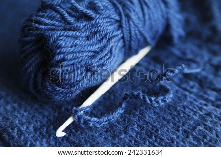 hook and yarn for knitting on a blue knitted cloth