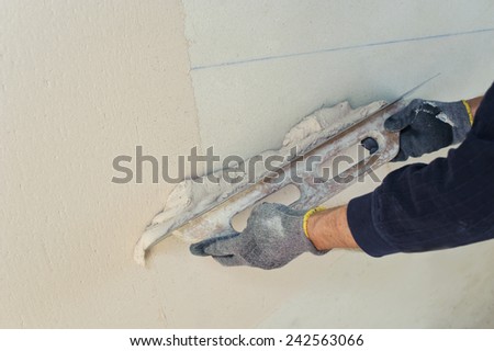 Gypsum puttying manually. Man\'s hands with a trowel applied and smooth plaster putty