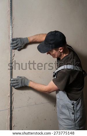 Man fixes a guide to align the walls with stucco in the future