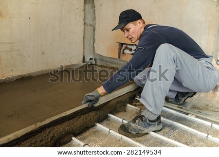 Man aligns fresh concrete with a ruler and a trowel