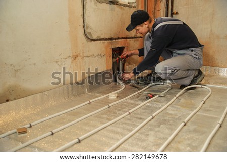 Man working installer connects the underfloor heating pipes