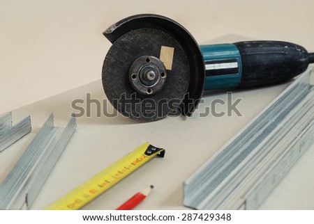 Detachable machine, metal profile, pencil, tape measure is on gypsum board