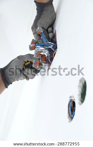 Electrician putting nuts on electrical wires in the box.
