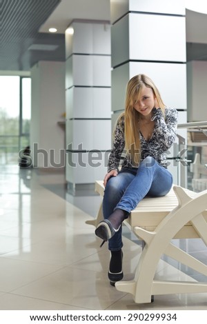 Young beautiful woman sitting on a bench in the commercial center