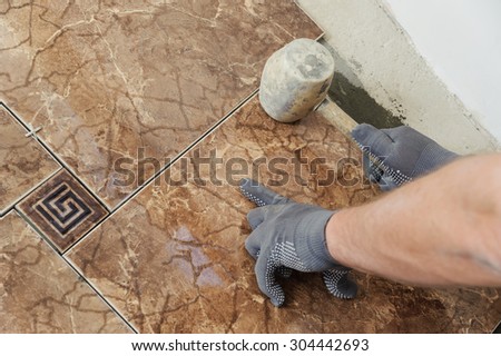 Laying Ceramic Tiles. Man knocks on the tiles with a rubber mallet