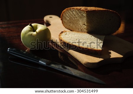 Still life. Homemade bread, an apple and a knife on the table