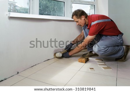 Laying the tiles. Tiler knocks a rubber mallet