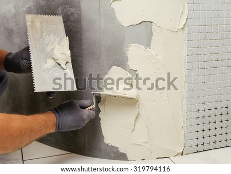 Installation of mosaic tiles. The worker puts adhesive on the base