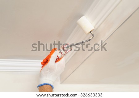 Painter paints the ceiling using a roller