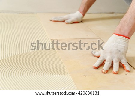 Laying plywood on the floor. The worker put a piece of plywood on the floor with glue.