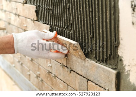 Installing the tiles on the wall. A worker putting tiles in the form of brick.