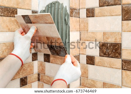 Installation of ceramic tiles. The tiler\'s hands are fixing the tile and forming Jolly Edge.