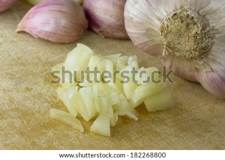a whole garlic bulb whit garlic cloves and chopped garlic on wooden cutting broad.