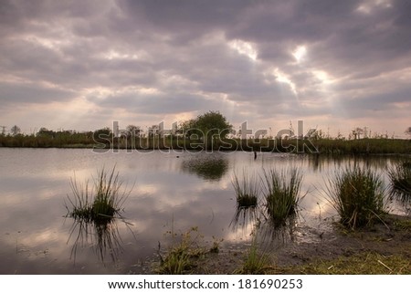 Clouds and sun rays passing above a lake giving a nice reflection on the water