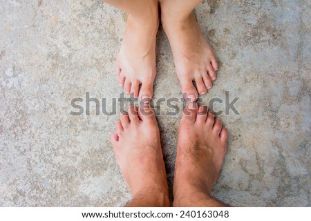 close up of couples bare feet stand on concrete ground