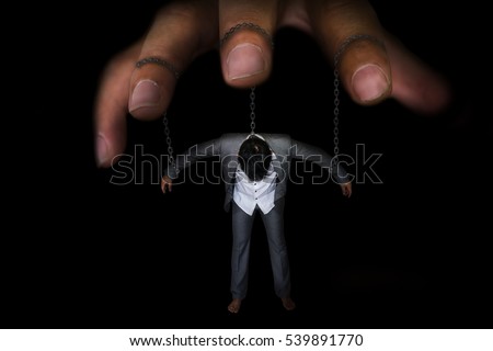 Business concept image of a businessman being controlled by puppet master with chain on neck , arm on black background with black shadow