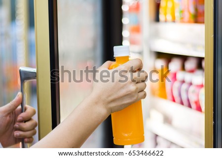 woman\'s hand open convenience store refrigerator shelves and pick product