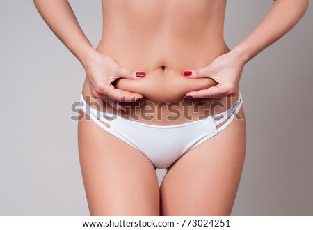 Fat female belly, woman holding her skin for cellulite check. Getting rid of belly fat and weight loss