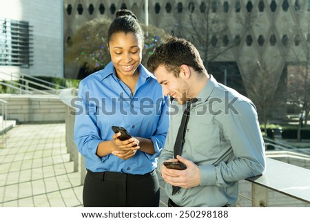 two business people sharing text message on cell phone including an African American woman and a caucasian man