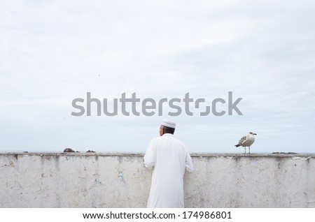 Isolated Moroccan man dressed in white traditional clothes looking in the distance