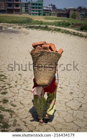 Female worker carrying a heavy bag filled with bricks in Kirtipur, Nepal