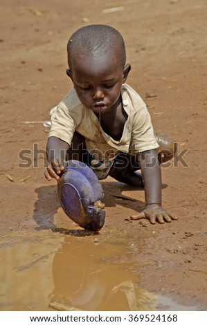 Kampala, Uganda-10 April 2007: Thirsty and hungry child is trying to get some water in a dirty pool.