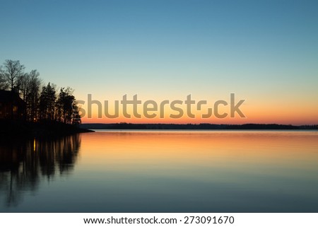 Cabin on the point reflecting in the lake with spring sunset colors