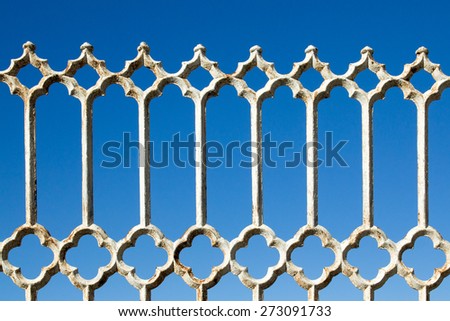 Old rusty white metal fence against bright blue sky