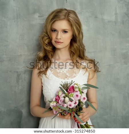 Beauty woman with wedding hairstyle and makeup. Flowers in hands. Bride fashion. Woman in white dress,perfect skin, blond hair. Girl with stylish haircut.