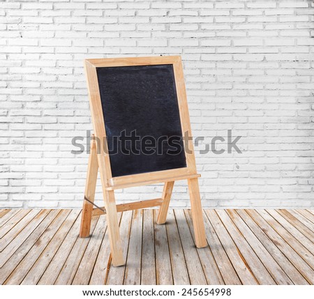 Blank blackboard on wood floor and white brick wall background