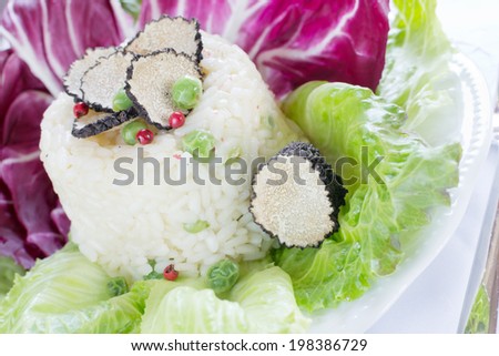 Risotto with green peas, black truffle and red pepper on leaves of salad