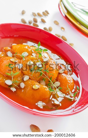 Apricot and almond with thyme in syrup on a red plate