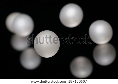 Mother of pearl beads pearls scattered on a black background.