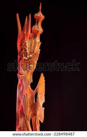 Wooden female figurine of the goddess in traditional folk costume on black background