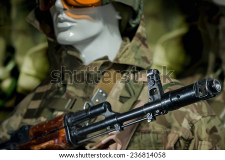 Mannequin in uniform in a military helmet and gun